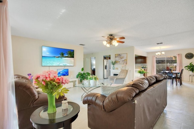 living room featuring a textured ceiling and ceiling fan with notable chandelier