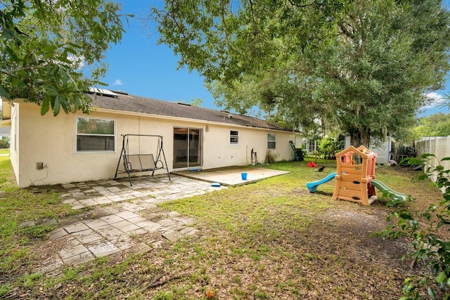 rear view of house featuring a playground, a yard, and a patio