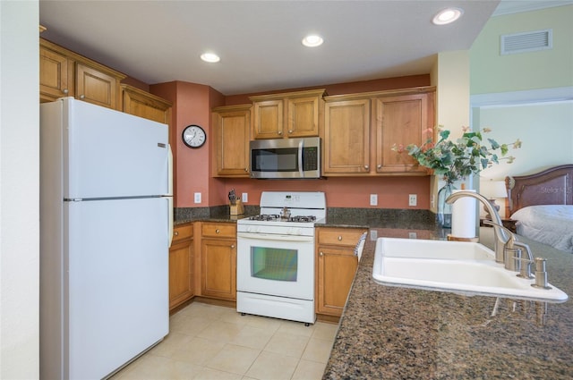 kitchen with dark stone countertops, sink, and white appliances