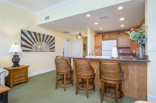 kitchen with dark carpet, white refrigerator, kitchen peninsula, a breakfast bar, and crown molding