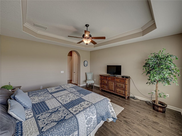 bedroom featuring a textured ceiling, a tray ceiling, dark hardwood / wood-style floors, and ceiling fan