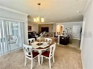 dining room featuring light carpet, crown molding, and an inviting chandelier