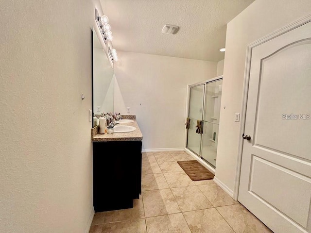 bathroom with vanity, a textured ceiling, tile patterned flooring, and an enclosed shower