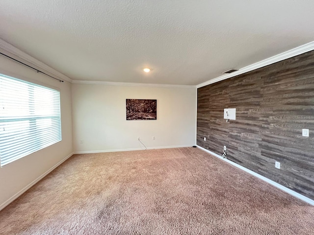 empty room featuring carpet floors, a textured ceiling, wood walls, and ornamental molding