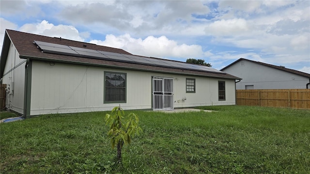 back of property featuring solar panels and a yard