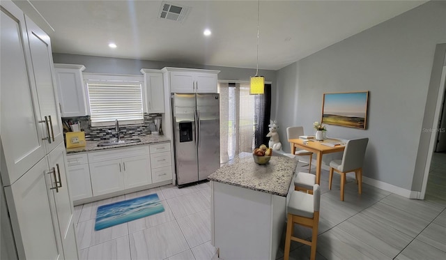 kitchen with sink, a kitchen island, stainless steel fridge, and white cabinetry