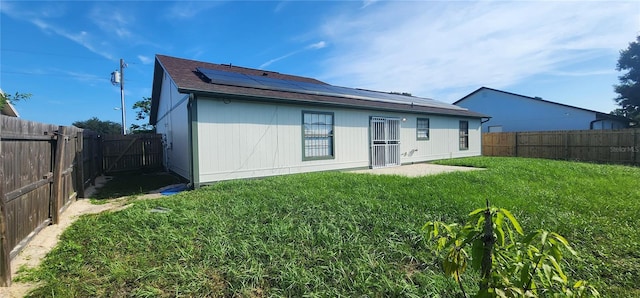 rear view of property featuring solar panels and a lawn