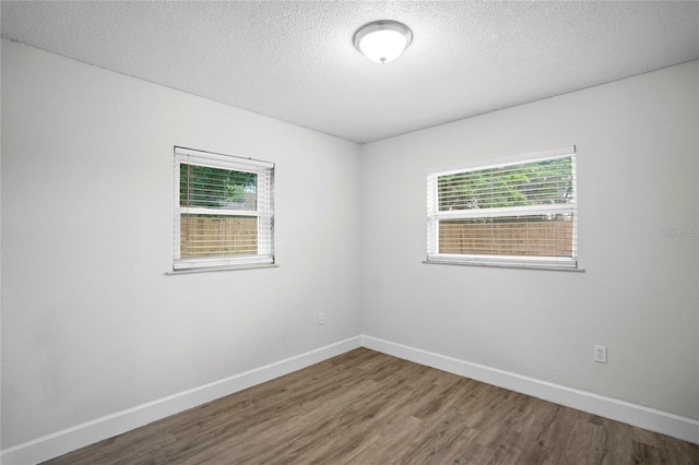 unfurnished room with hardwood / wood-style flooring, a textured ceiling, and a healthy amount of sunlight