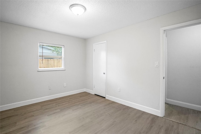 spare room featuring wood-type flooring and a textured ceiling