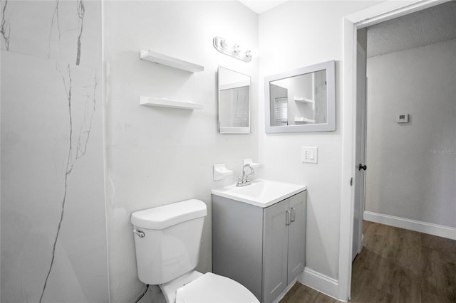 bathroom with wood-type flooring, vanity, toilet, and a textured ceiling