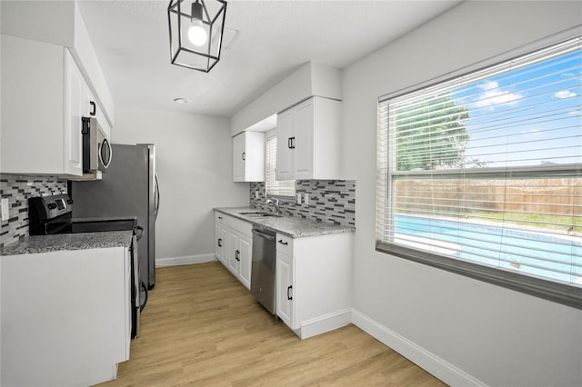 kitchen with appliances with stainless steel finishes, light hardwood / wood-style floors, decorative backsplash, and white cabinetry