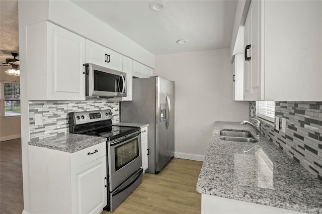 kitchen with white cabinets, stainless steel appliances, sink, and light hardwood / wood-style flooring