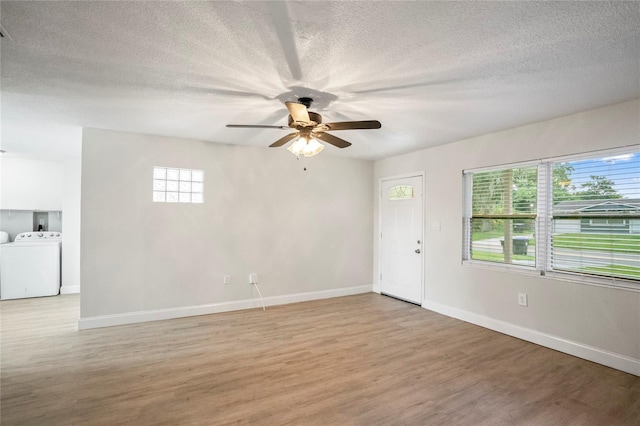 empty room with a textured ceiling, light hardwood / wood-style floors, ceiling fan, and washing machine and clothes dryer