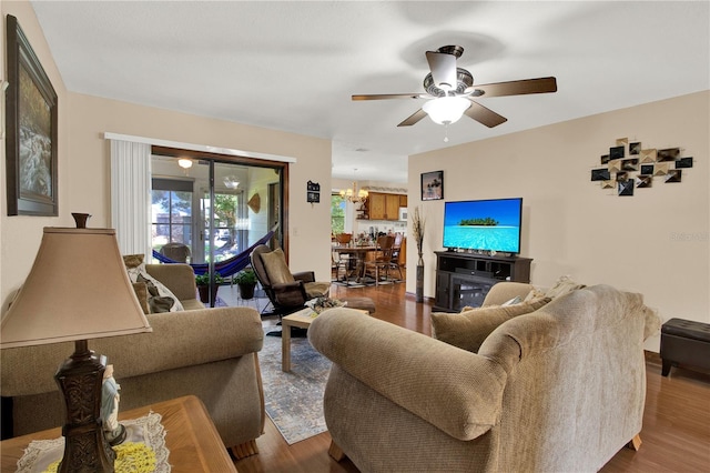 living room with ceiling fan with notable chandelier and hardwood / wood-style floors