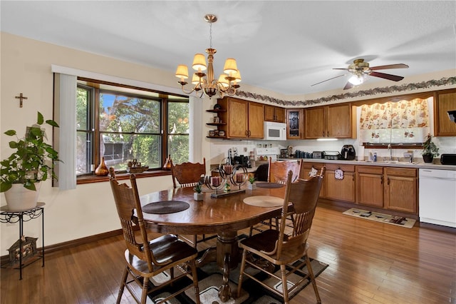 dining area featuring dark hardwood / wood-style floors, ceiling fan with notable chandelier, and sink