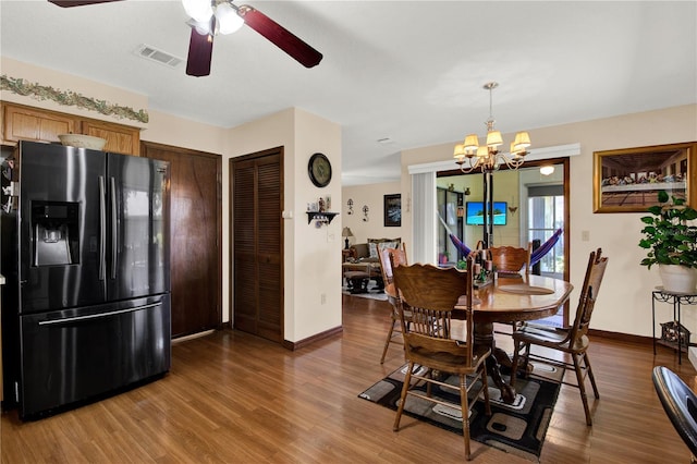 dining space featuring ceiling fan with notable chandelier and wood-type flooring