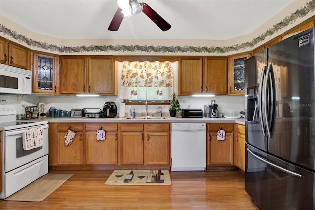 kitchen with tasteful backsplash, white appliances, light wood-type flooring, ceiling fan, and sink