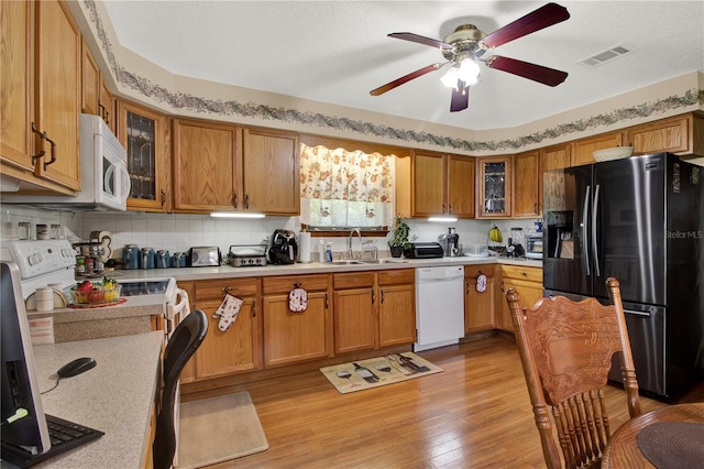 kitchen with backsplash, white appliances, ceiling fan, light hardwood / wood-style flooring, and sink