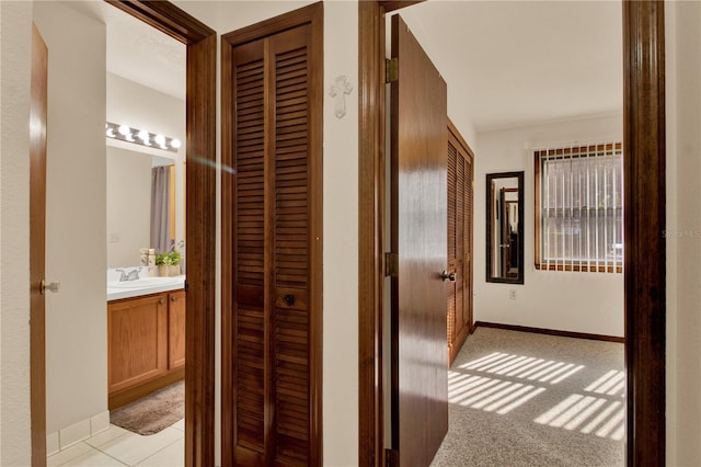 hallway with light carpet and sink