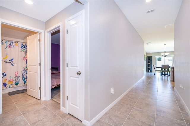 hall with an inviting chandelier and light tile patterned flooring