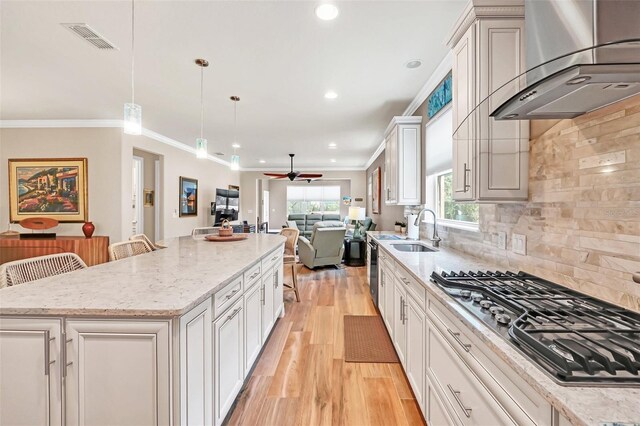 kitchen featuring ceiling fan, stainless steel gas cooktop, a kitchen island, a kitchen breakfast bar, and decorative backsplash