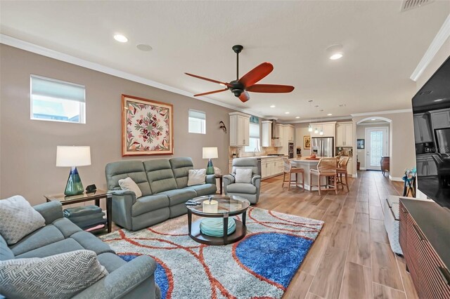 living room with ceiling fan, light wood-type flooring, plenty of natural light, and crown molding