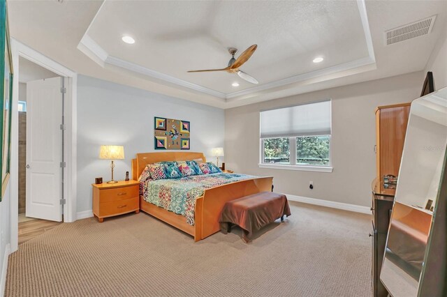 bedroom with ornamental molding, a tray ceiling, ceiling fan, and light colored carpet