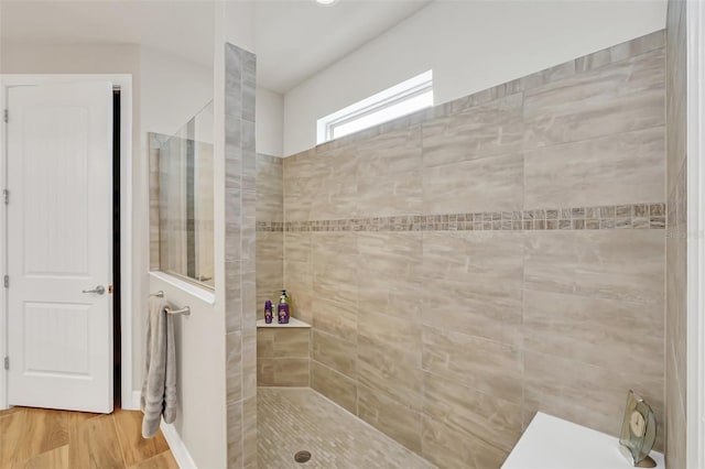 bathroom with tiled shower and hardwood / wood-style flooring