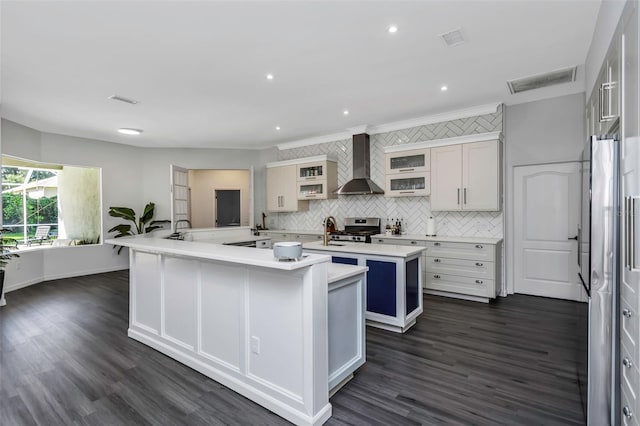 2228 Valrico Forest Dr, Valrico, FL 33594 - kitchen featuring wall chimney exhaust hood, dark hardwood / wood-style flooring, stainless steel range with gas cooktop, crown molding, and a center island with sink