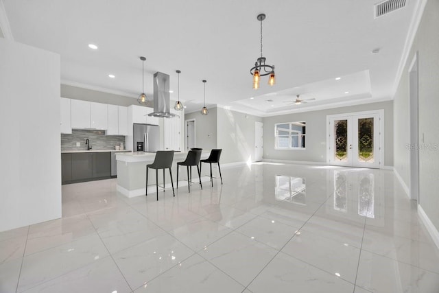 living room with ceiling fan, a raised ceiling, ornamental molding, sink, and french doors