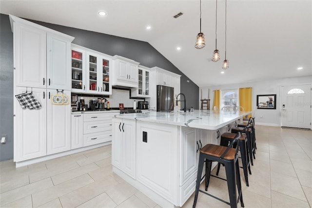 kitchen with pendant lighting, lofted ceiling, a large island, white cabinetry, and a breakfast bar area