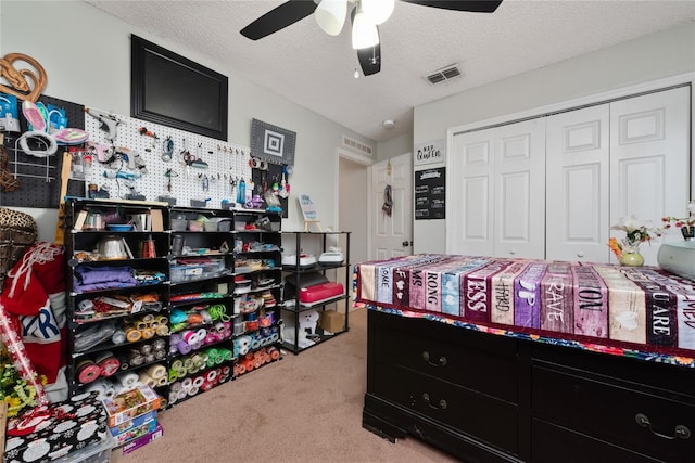 bedroom featuring a closet, ceiling fan, light colored carpet, and a textured ceiling