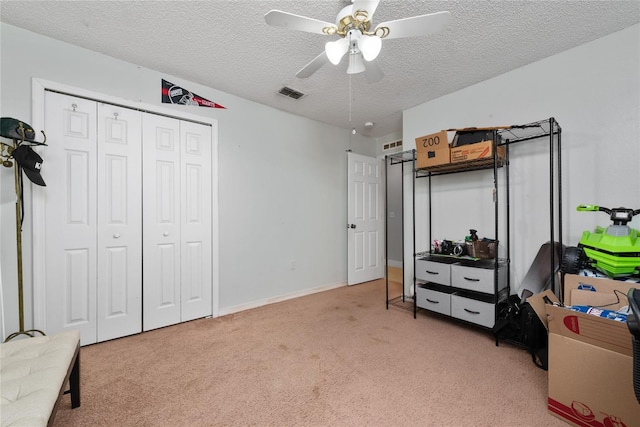 carpeted bedroom featuring a closet, ceiling fan, and a textured ceiling