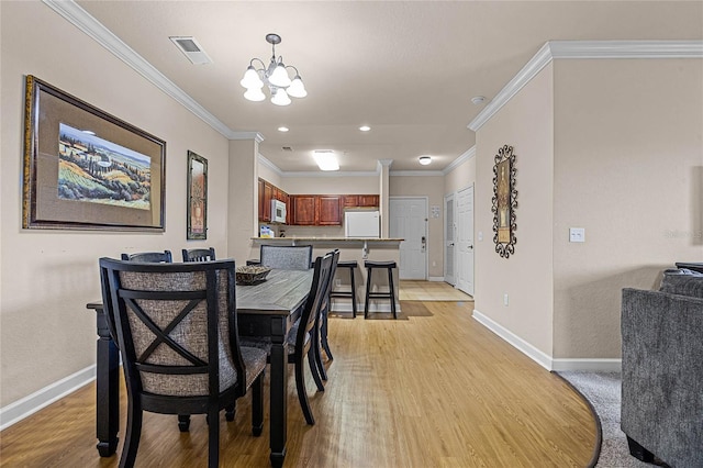 dining room with light hardwood / wood-style flooring, a notable chandelier, and crown molding