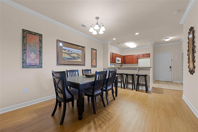 dining area featuring a notable chandelier, light wood-type flooring, and ornamental molding