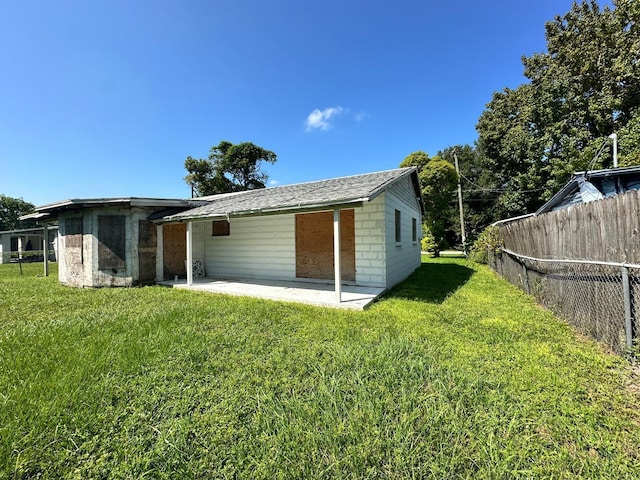 rear view of property with a patio area, concrete block siding, a yard, and fence