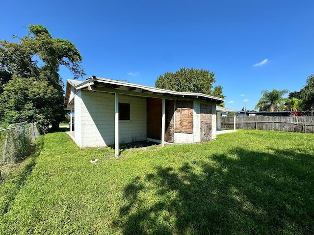 back of house with a lawn, concrete block siding, and a fenced backyard