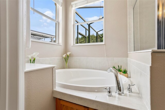 bathroom featuring plenty of natural light and tiled bath