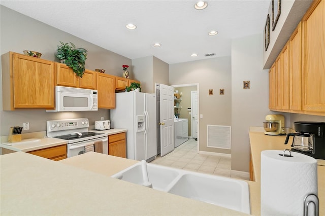 kitchen with washing machine and dryer, white appliances, and sink