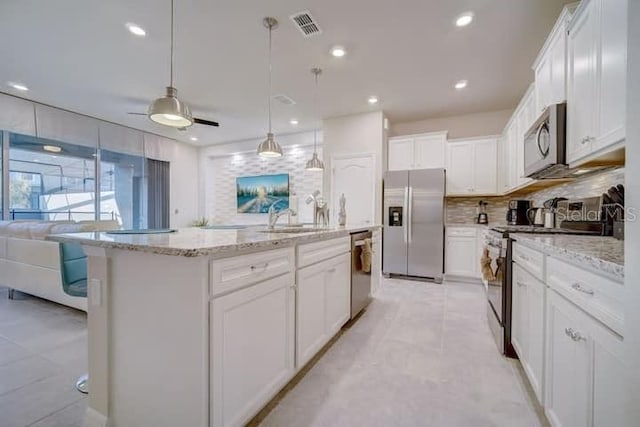 kitchen featuring white cabinets, stainless steel appliances, ceiling fan, decorative light fixtures, and a kitchen island with sink