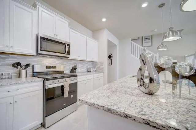 kitchen featuring white cabinetry, backsplash, appliances with stainless steel finishes, decorative light fixtures, and light stone countertops