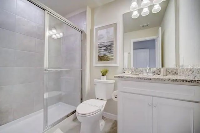 bathroom with walk in shower, vanity, and toilet