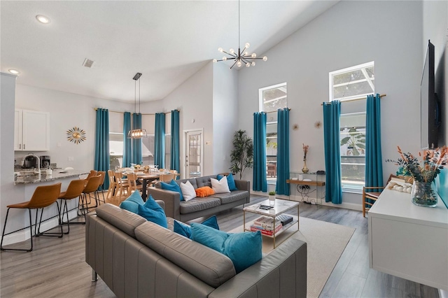 living room featuring an inviting chandelier, light hardwood / wood-style floors, and a healthy amount of sunlight