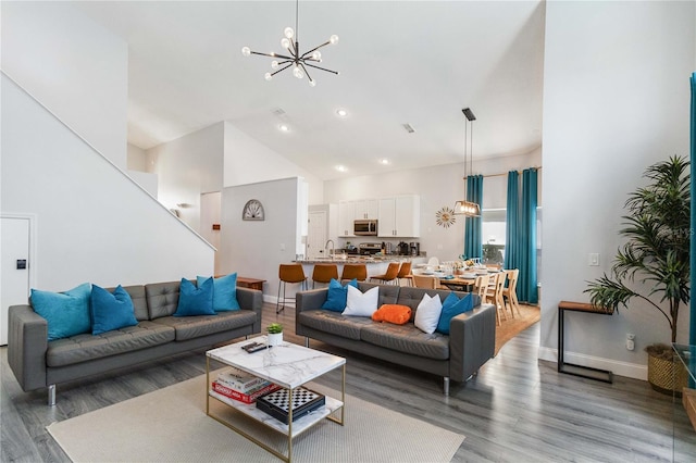 living room featuring high vaulted ceiling, a chandelier, dark hardwood / wood-style floors, and sink