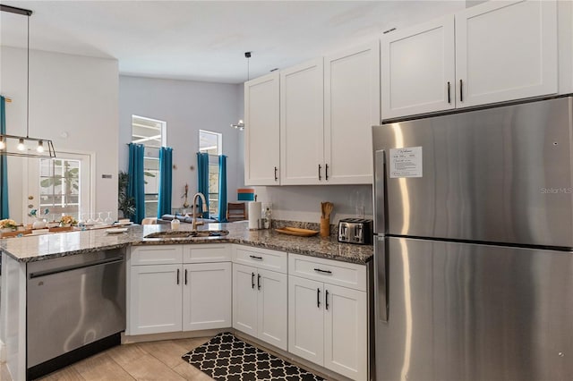 kitchen featuring decorative light fixtures, appliances with stainless steel finishes, sink, and white cabinetry