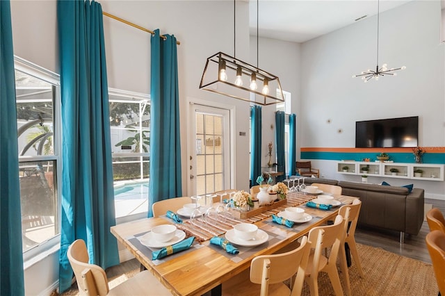 dining room with an inviting chandelier, wood-type flooring, and a high ceiling