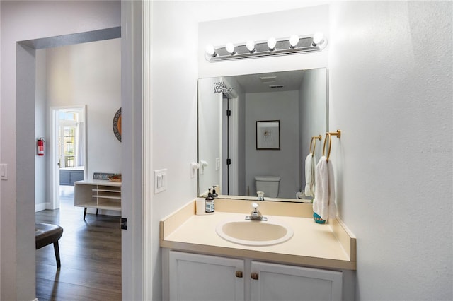 bathroom with wood-type flooring, vanity, and toilet