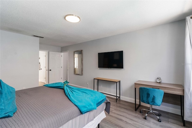 bedroom with a textured ceiling and light wood-type flooring