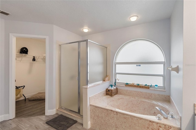 bathroom with wood-type flooring, separate shower and tub, and a textured ceiling