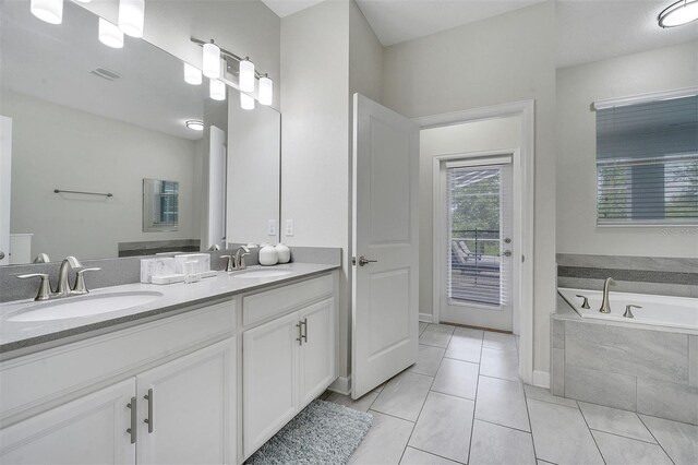 bathroom with tile patterned flooring, tiled bath, and vanity